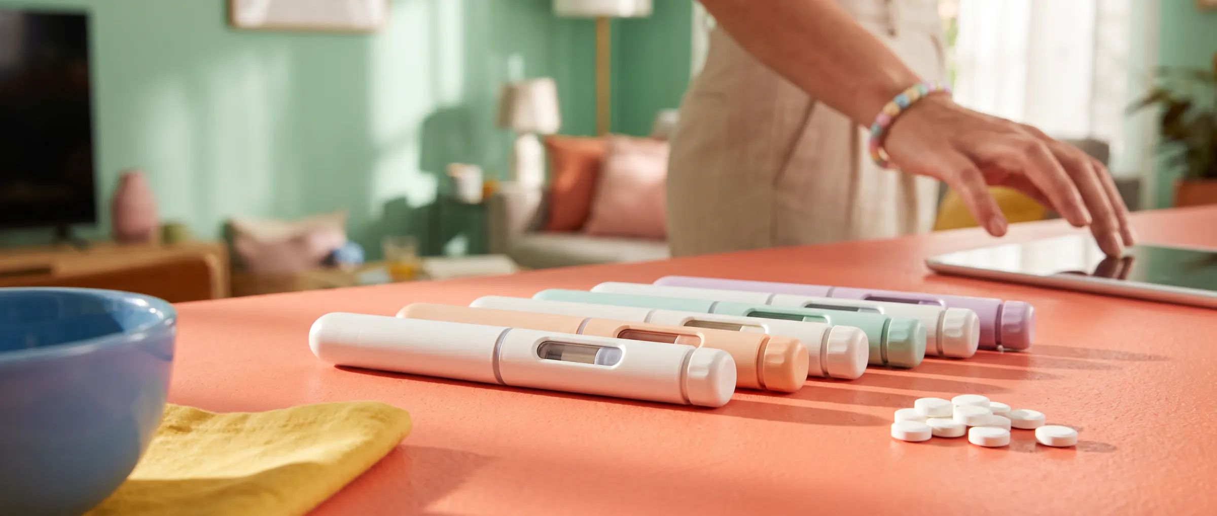 A row of plain injection pens and a few white tablets on a sunny table